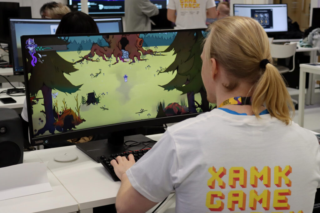 Opiskelija esittelee peliprojektia näytöltä.